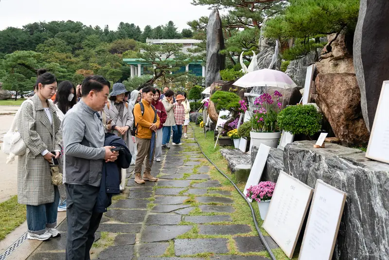 산책로에 줄지어 서서 시 작품을 감상하는 관람객들